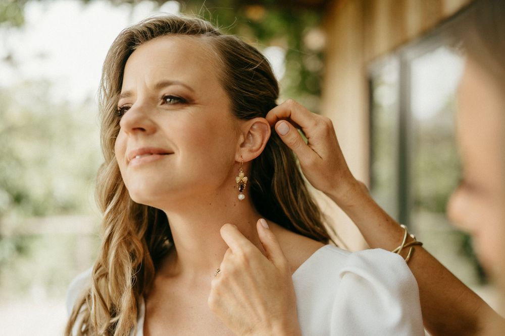 Final touches being made to wedding day hair and accessories in warm natural light.