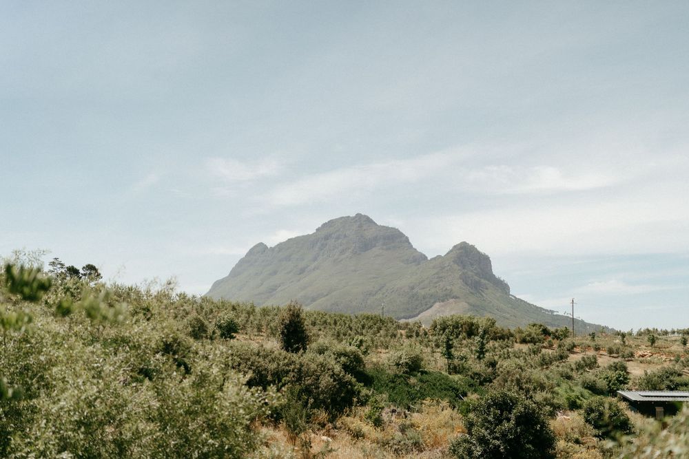 Scenic mountain landscape with desert brush under cloudy sky.