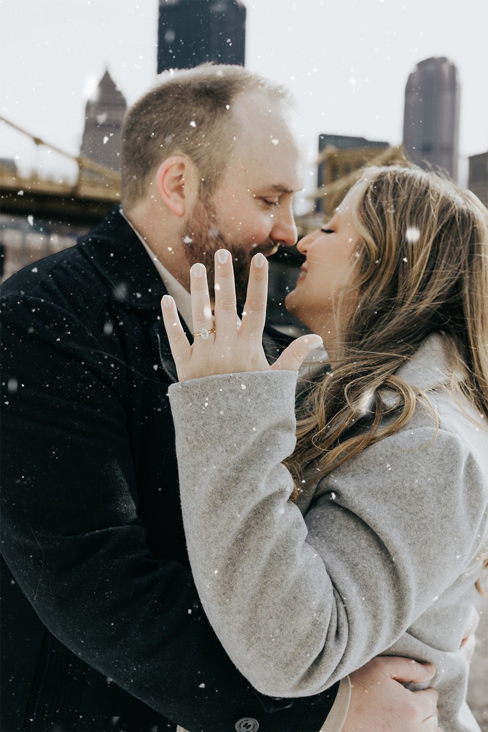 Romantic winter engagement photo with snowflakes falling in an urban setting. Pittsburgh Weddings by Pittsburgh Photographers