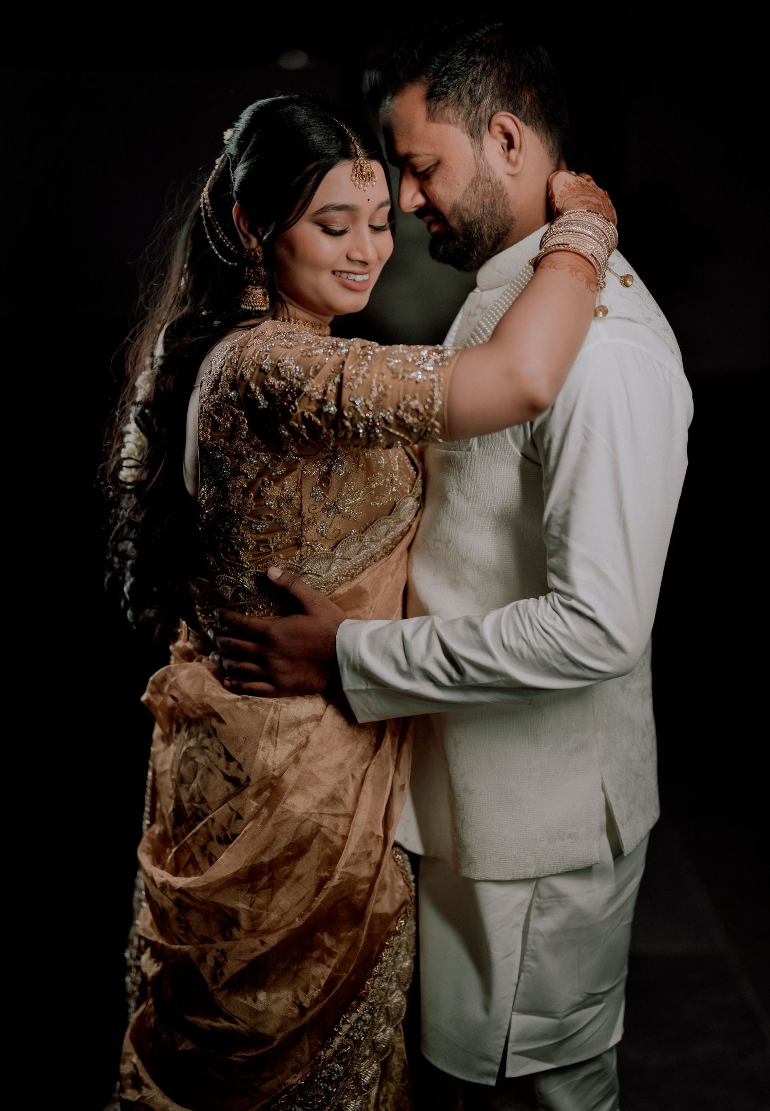 Romantic dance pose featuring traditional Indian wedding attire in champagne and white colors.
