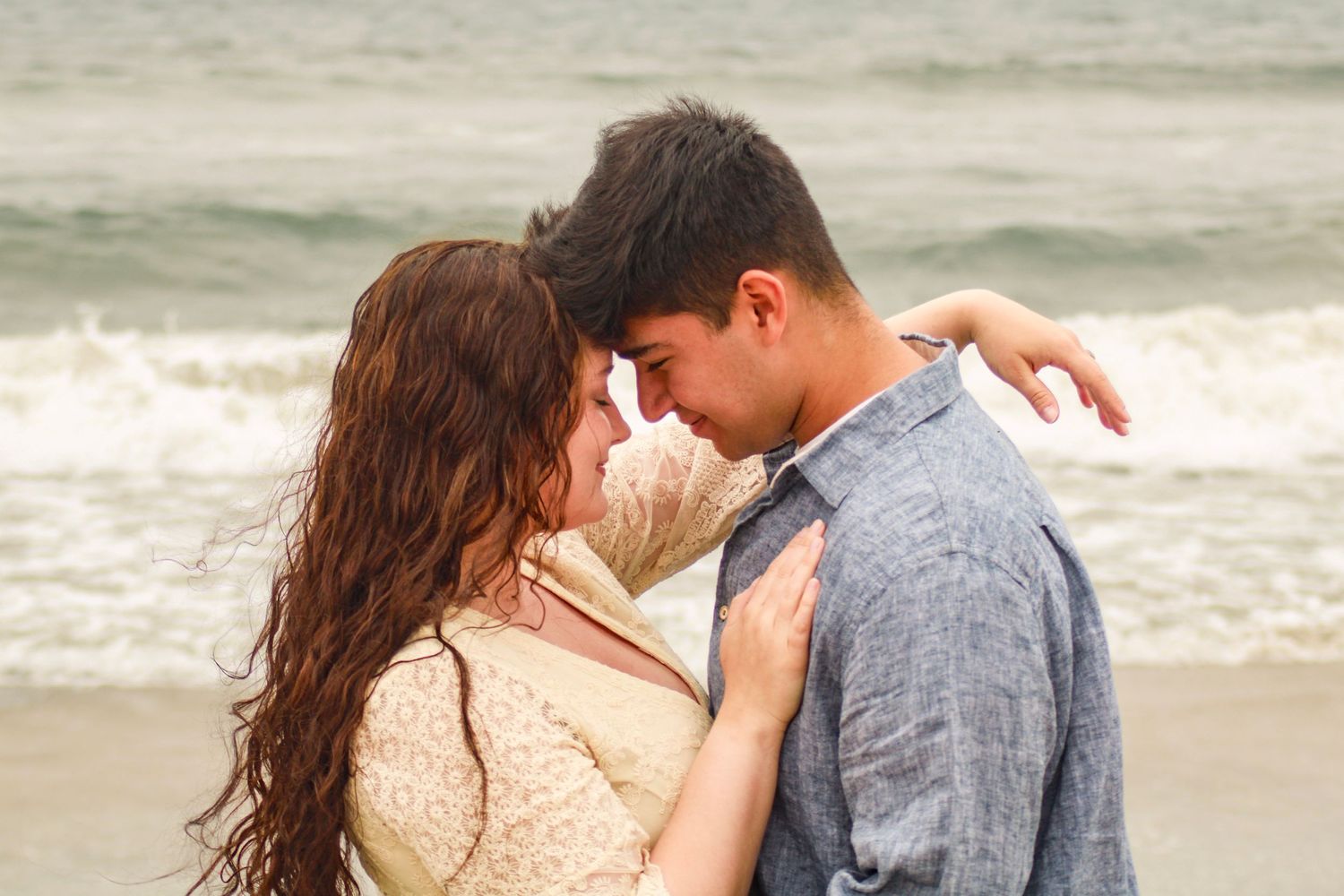 Romantic couple embracing on a sandy beach at sunset.