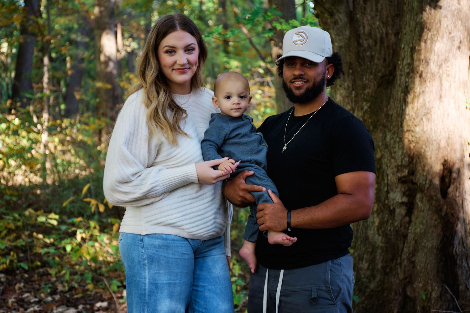 Family of three sharing a tender moment together in a wooded setting.