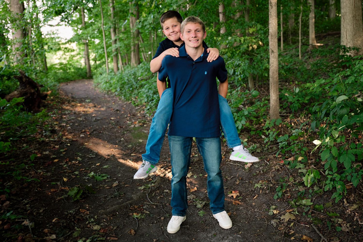Two people playfully posing on a forested trail with trees in the background.