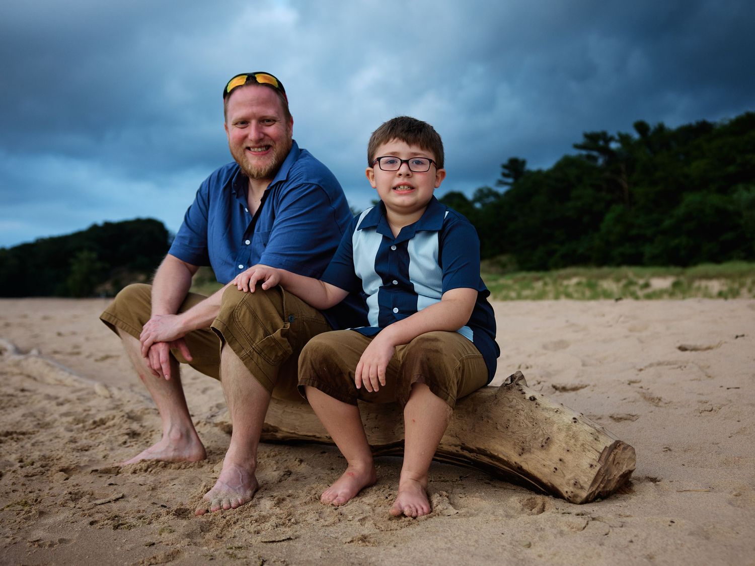 People sitting on a sandy beach with their feet visible against a cloudy sky background.