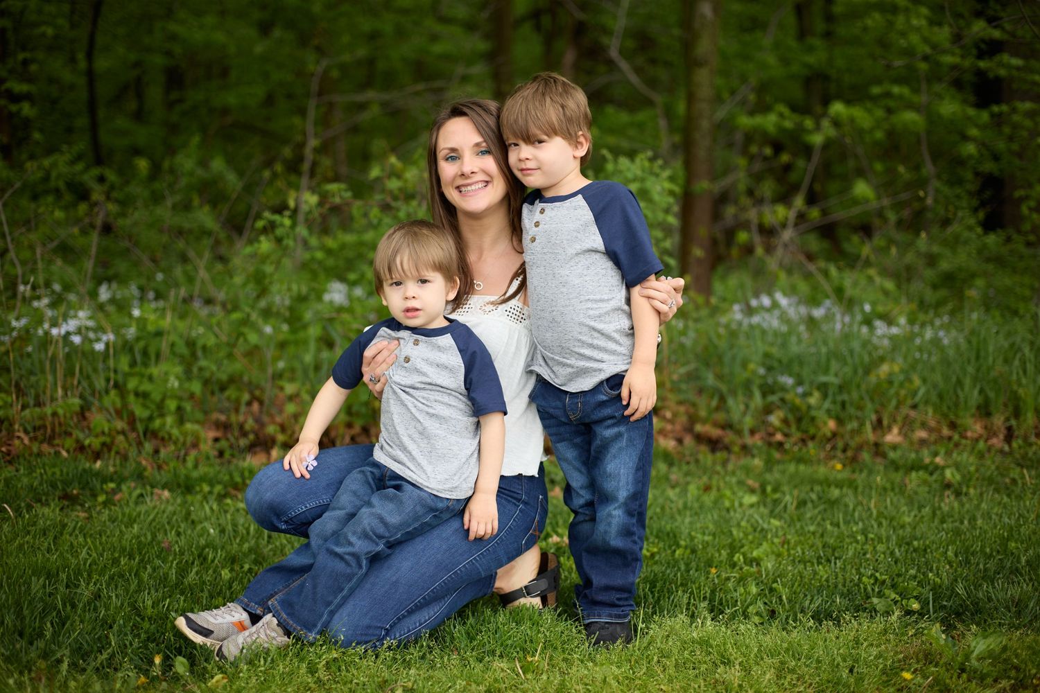 Spring outdoor portrait in a wooded setting with wildflowers blooming in the background.