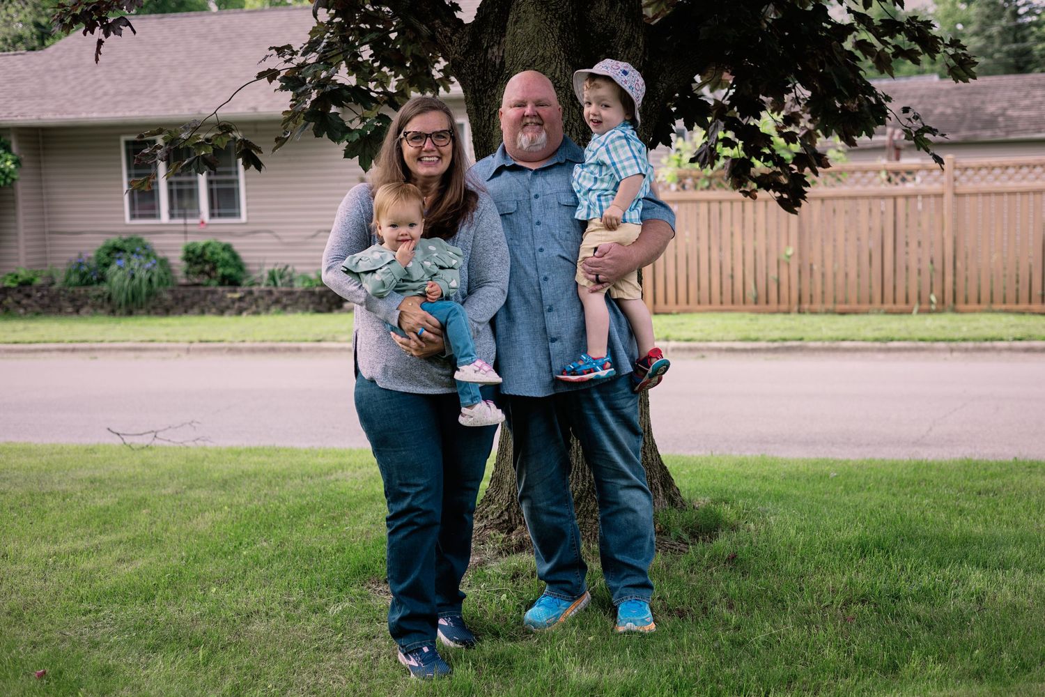 A family posing together on their front lawn on a summer day.