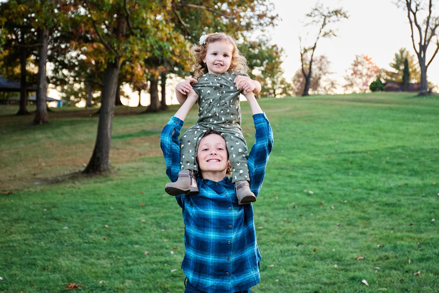 Playful moment captured outdoors as child is lifted high in the air.
