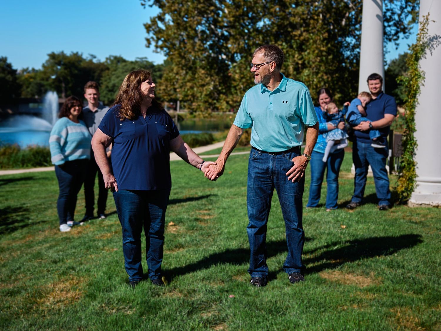 A series of candid outdoor photos showing people in blue clothing interacting on a grassy hillside on a sunny day.