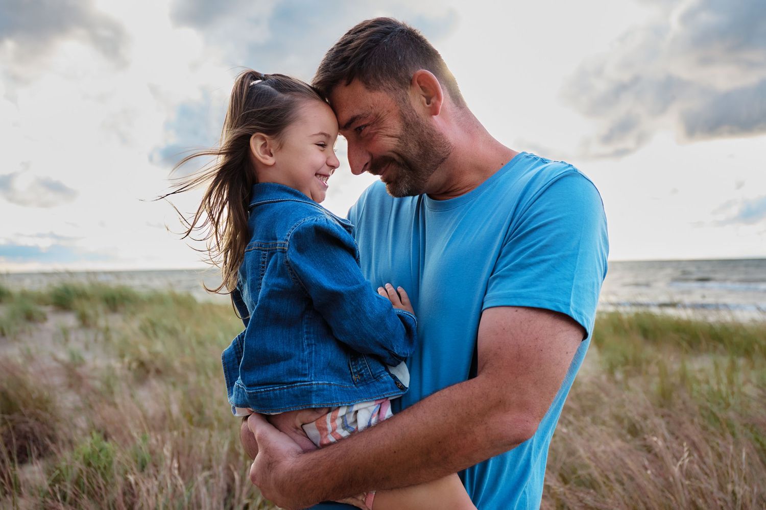 A tender moment between parent and child against a coastal background.