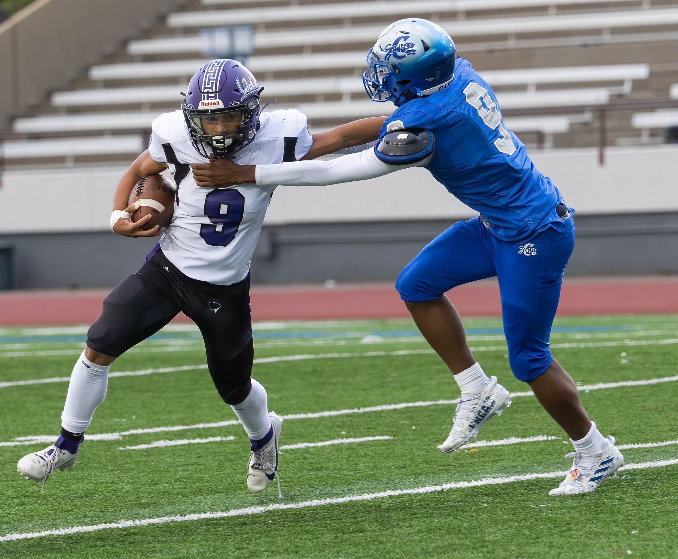 Football players from opposing teams engage in tackle during competitive game.