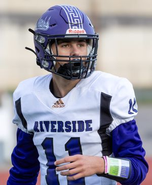 Football player in purple and white uniform stands ready on field.