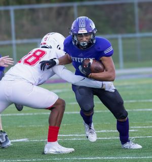 Football player in blue jersey battles defender in white uniform during intense run play.