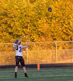 Player preparing to catch football with vibrant yellow fall foliage in background.
