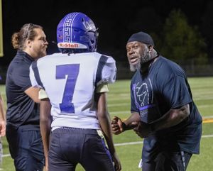 Coaches provide instruction during nighttime football game.