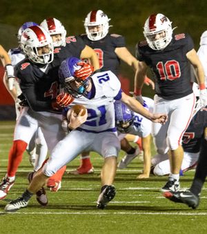 Multiple players converge to tackle ball carrier during intense football play.