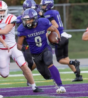 Running back in purple jersey number 9 carries ball through defensive line.