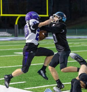 Two football players battle for possession during competitive night game.