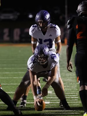 Football players line up in formation before snap during nighttime game.
