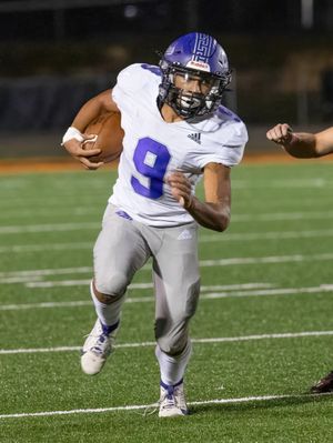 Player in white jersey number 9 runs with football during night game on artificial turf field.