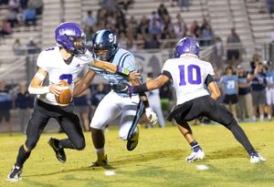 Football players in purple and light blue uniforms clash during an intense nighttime game.