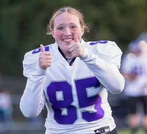 Football player in white jersey with number 85 gives thumbs up on sideline.