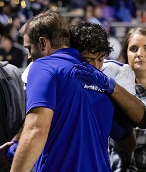Two people embrace in an emotional moment during a football game.