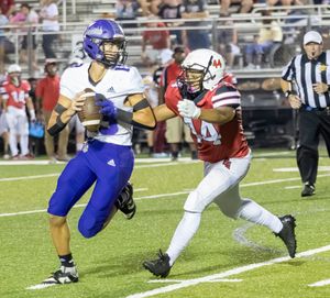 Football players from opposing teams compete as one runs with the ball while being chased.