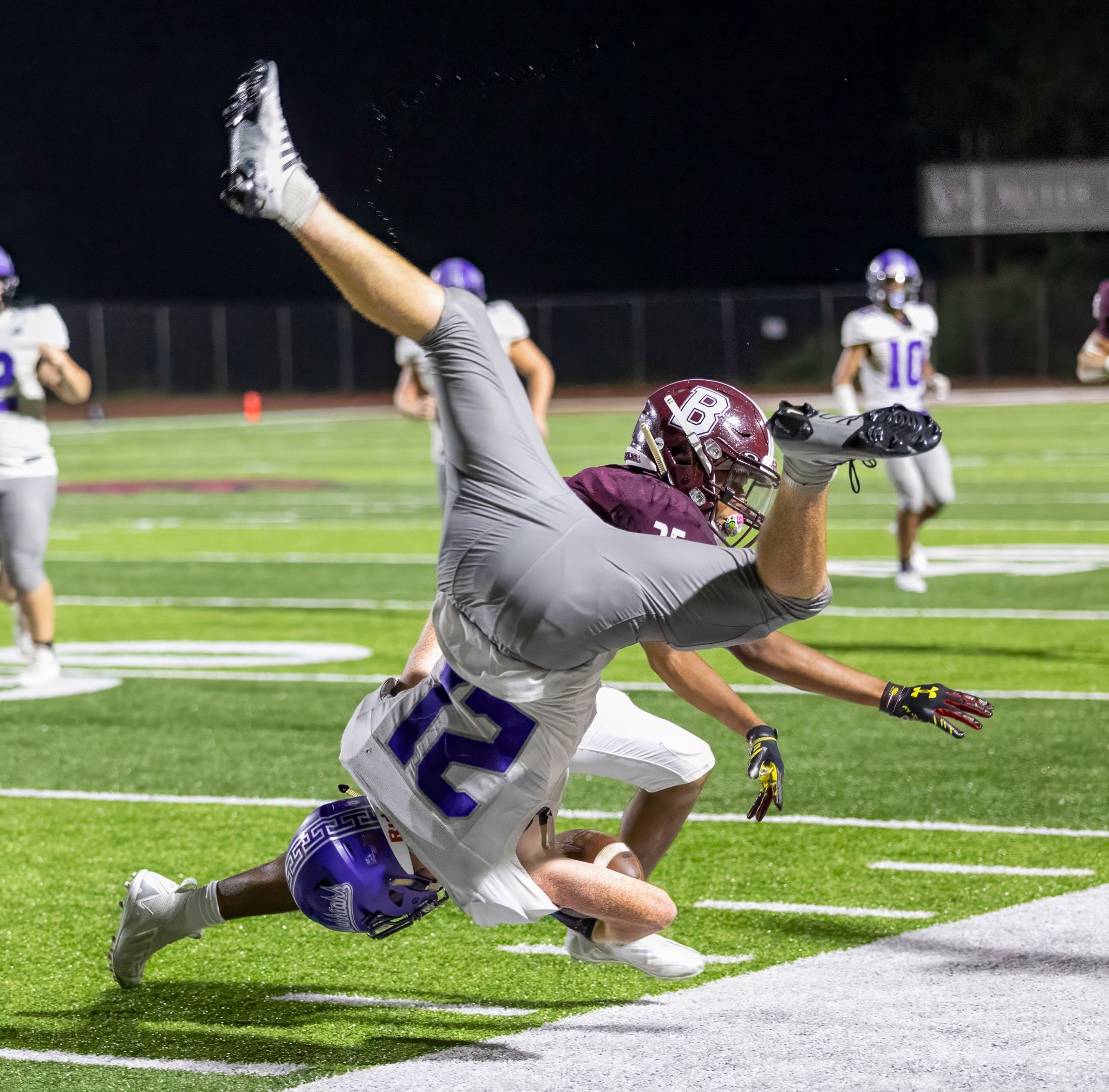 Football player airborne during diving tackle attempt in competitive game.
