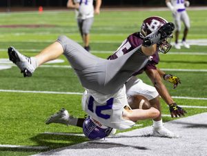 Two football players collide during tackle attempt in night game.