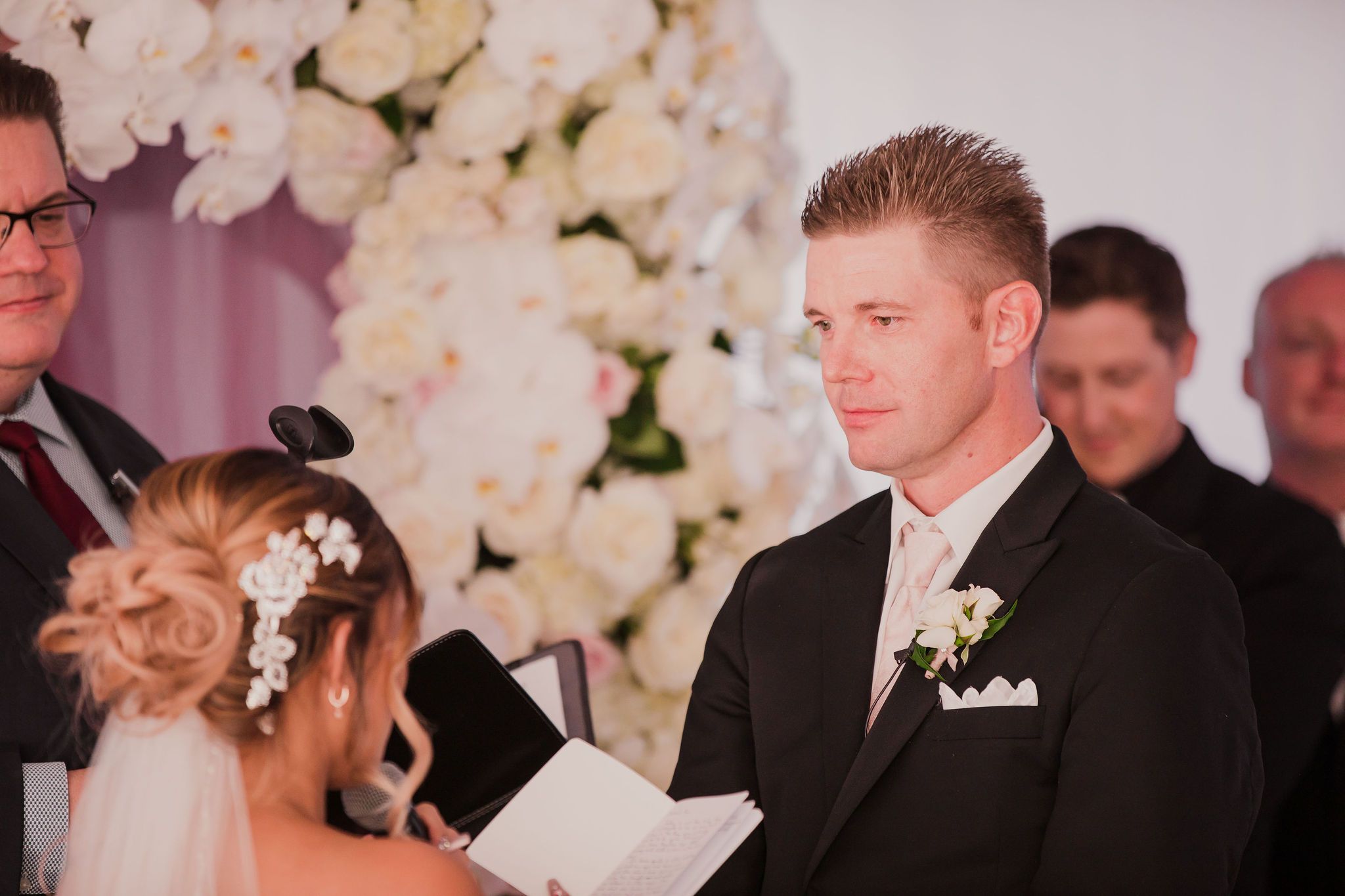 A series of wedding ceremony photos showing emotional moments between the couple and guests at a floral-decorated venue.