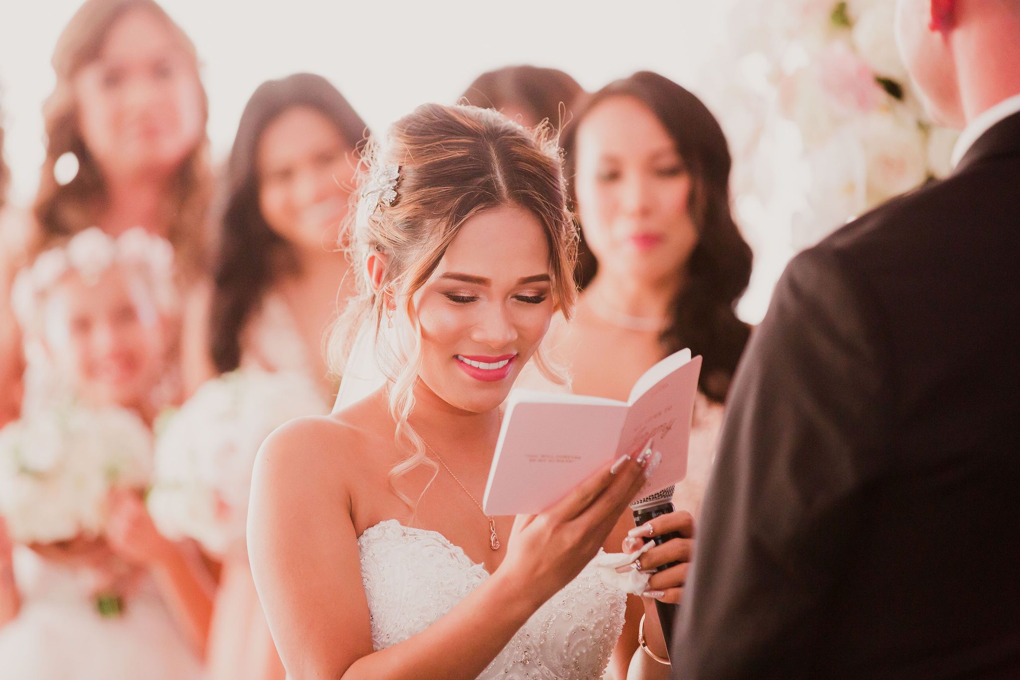 Wedding guests enjoying candid moments during a reception with soft pink lighting and floral decorations.
