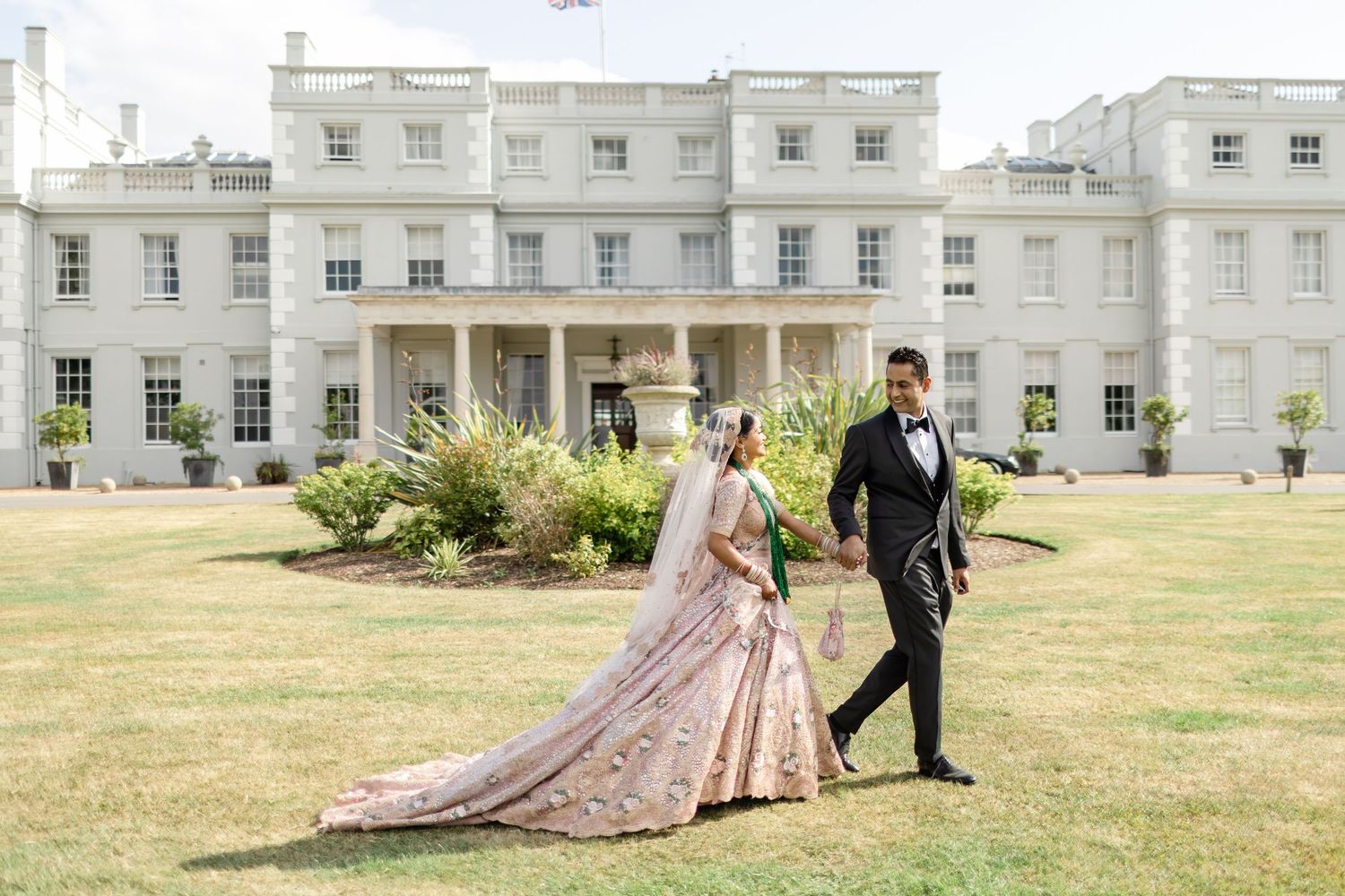 Editorial-style portrait of a Muslim couple in traditional attire against the grand architecture of De Vere Wokefield Estate