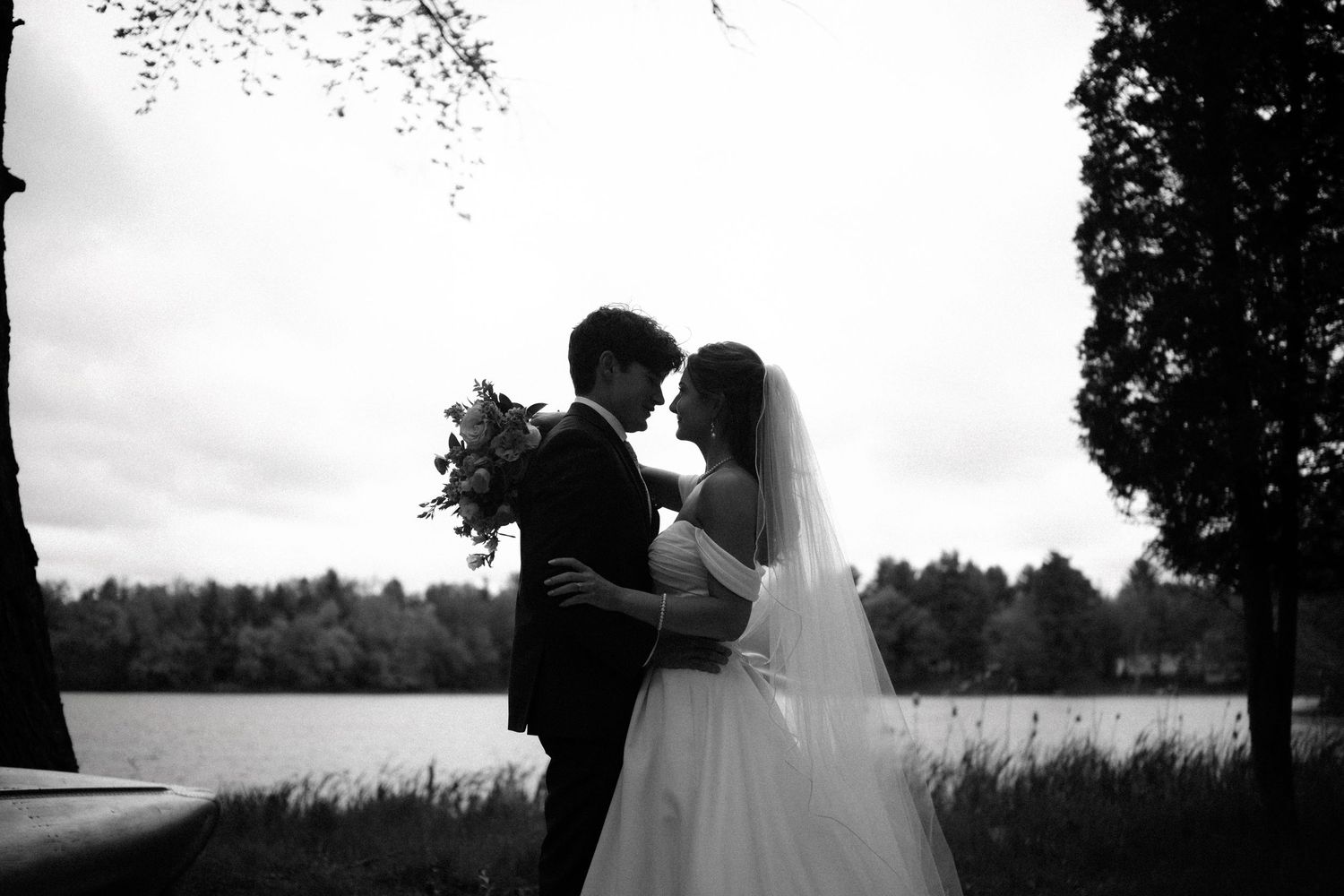 A romantic silhouette of a couple embracing in front of a scenic landscape during sunset.