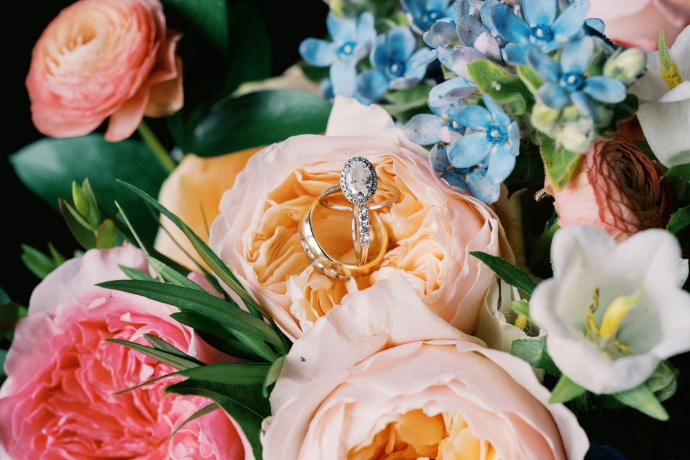 Elegant floral arrangement featuring coral and peach garden roses with blue hydrangeas and delicate greenery.