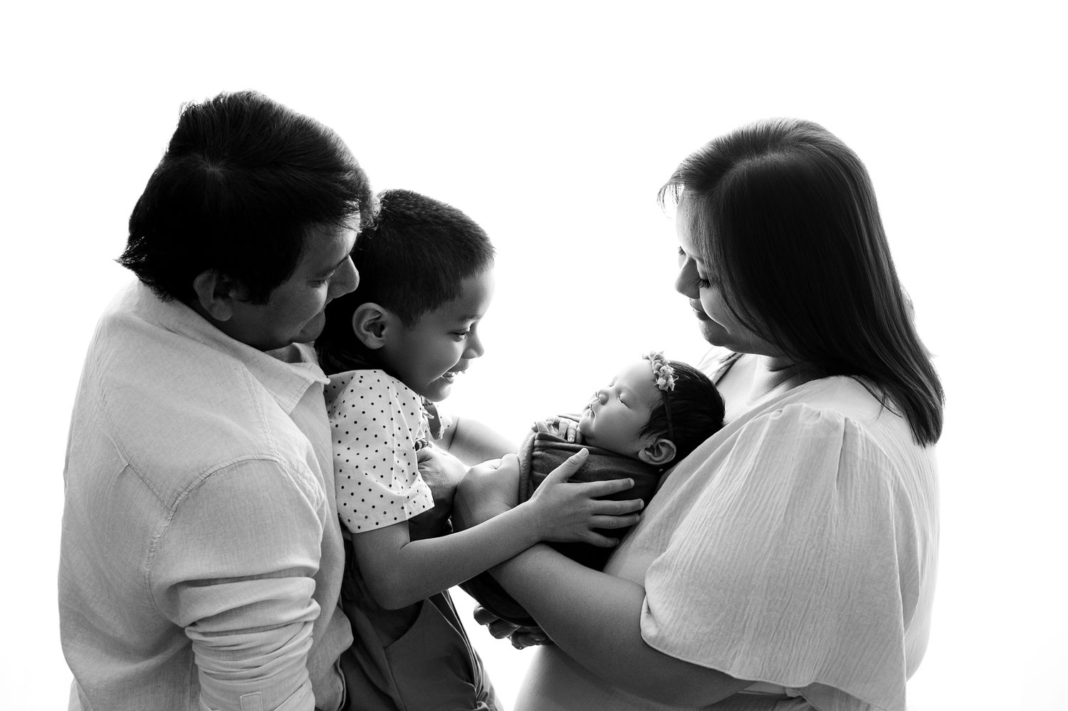 Black and white photo of a family moment with a baby being held and cared for by loved ones.