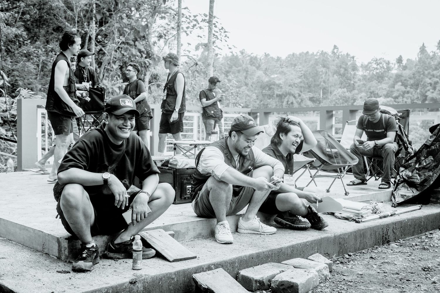 A group of skateboarders resting and hanging out at a skate park in black and white photography.