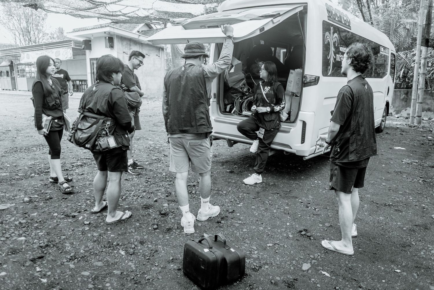 A group of people gather outdoors near parked vehicles during what appears to be a casual event or meetup.