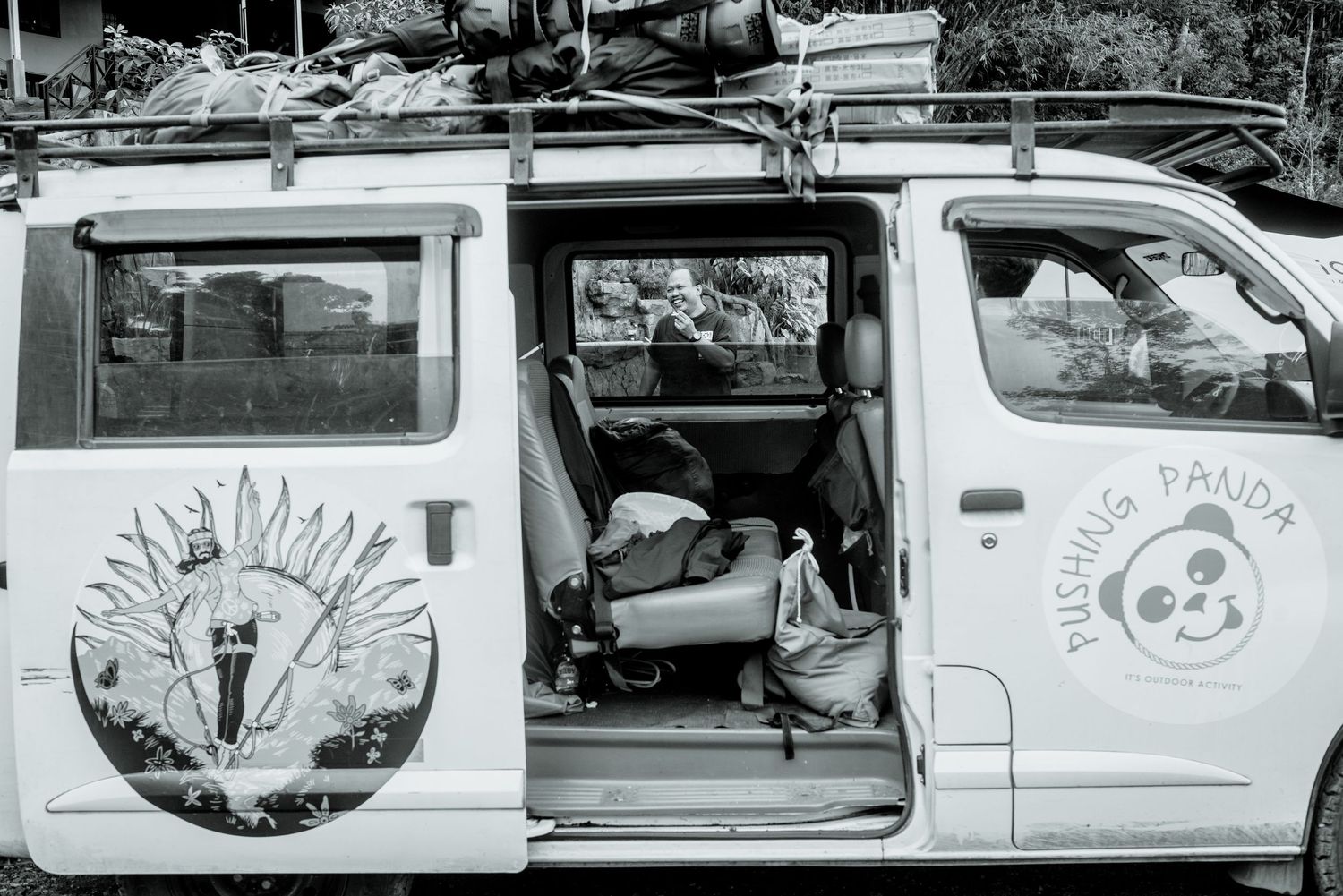 A black and white photograph shows several parked white vans with business logos displayed on their sides.