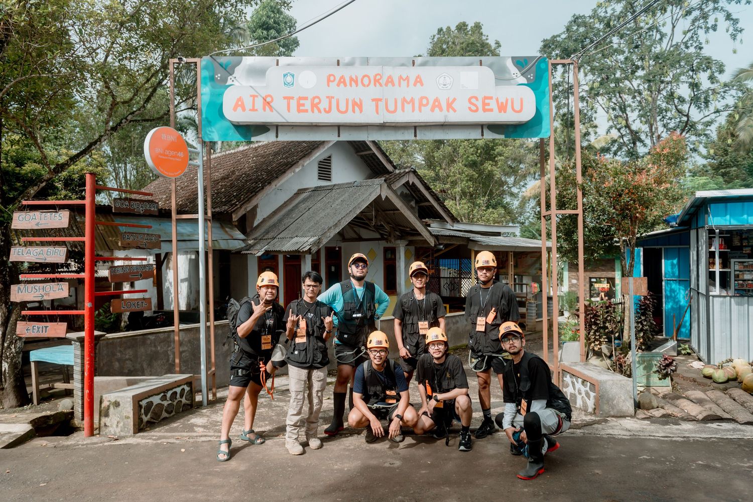 A group of people gather outside a rustic shop entrance with a blue and white sign.