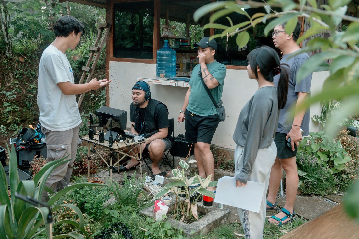 A group gathers outdoors for a workshop or class in a lush garden setting with notebooks and supplies.