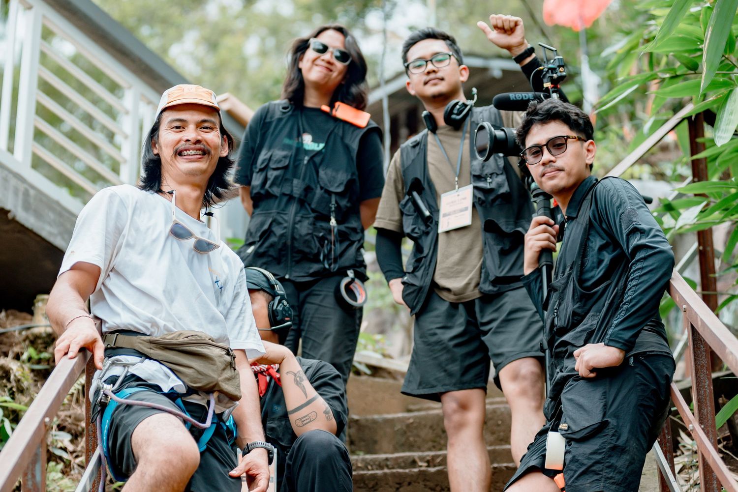 A group of people gather outdoors in casual attire, smiling and enjoying themselves in a natural setting.