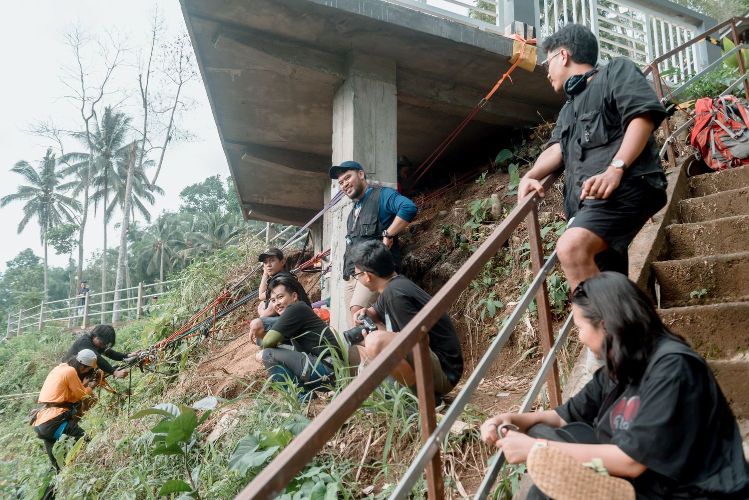 Emergency rescue workers use ropes and equipment to assist in a mudslide evacuation operation on a steep hillside.