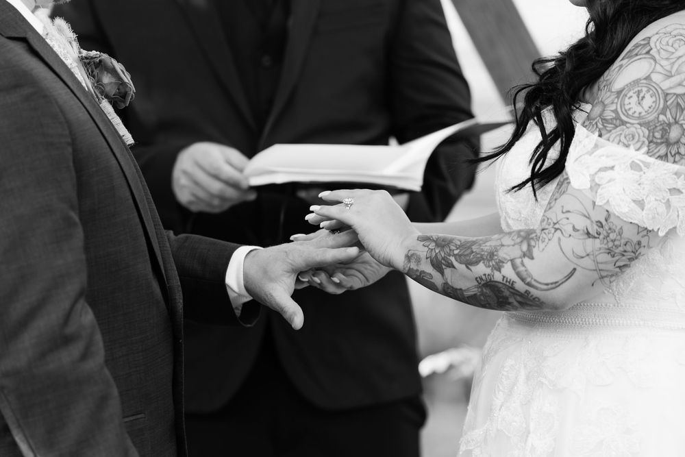 Black and white collage of wedding ceremony moments showing hands exchanging rings and holding bouquets.