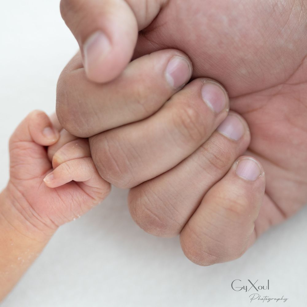 Close-up series of tiny baby fingers being gently held by adult hands.