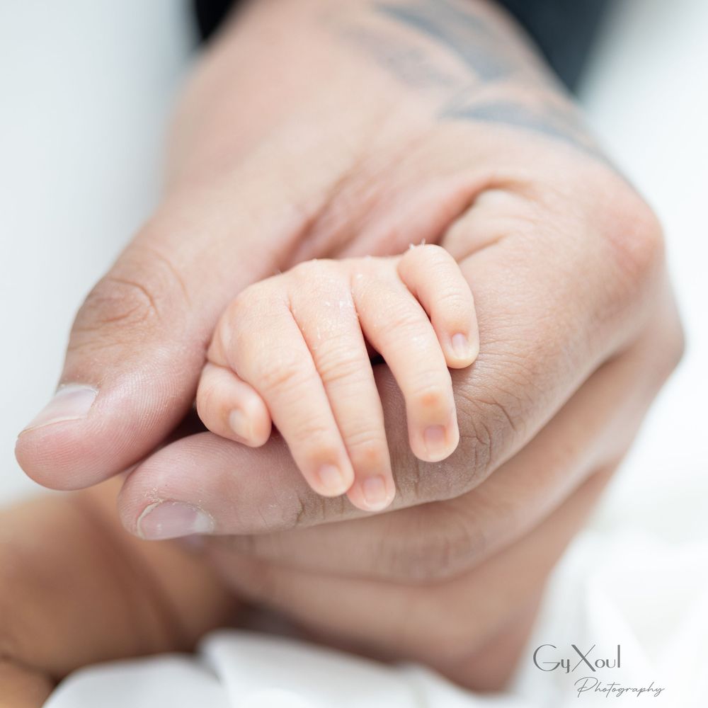 Close-up black and white photo of gentle hands holding a small baby's foot.