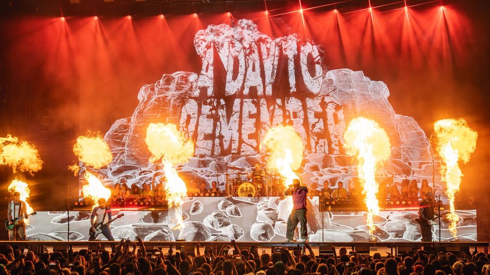 Concert stage illuminated with dramatic red lighting and pyrotechnic effects during a live performance.