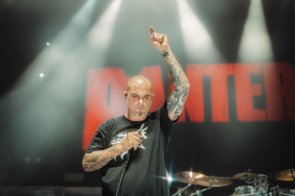 Drummer performs energetically on stage with dramatic lighting and multiple camera angles showing intense performance.