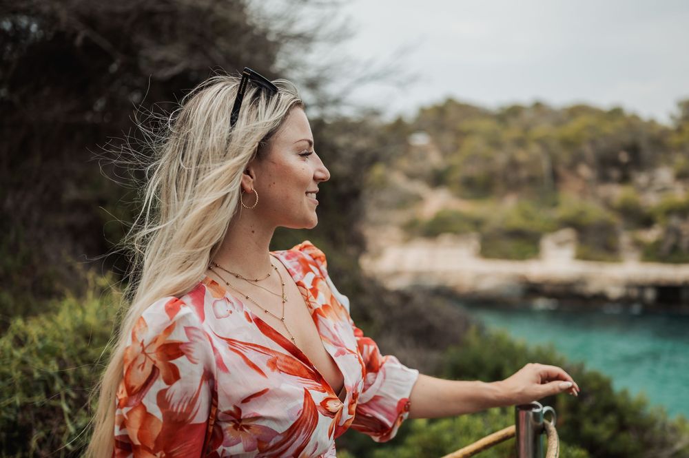 A sequence of photos showing someone in a flowing coral dress walking along a scenic coastal path.