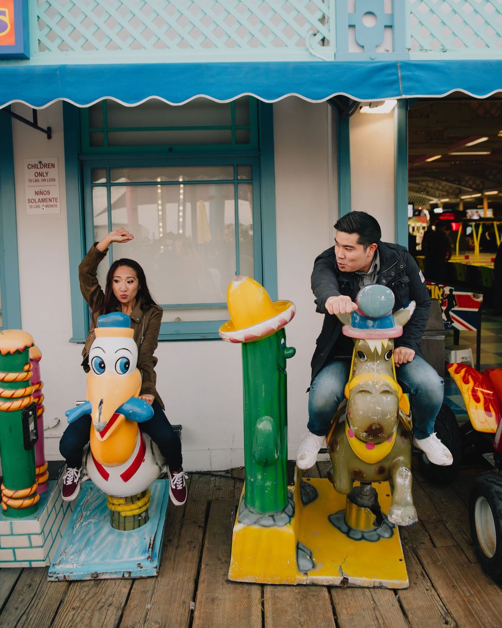 Couple riding colorful carousel animals at a fun amusement arcade.