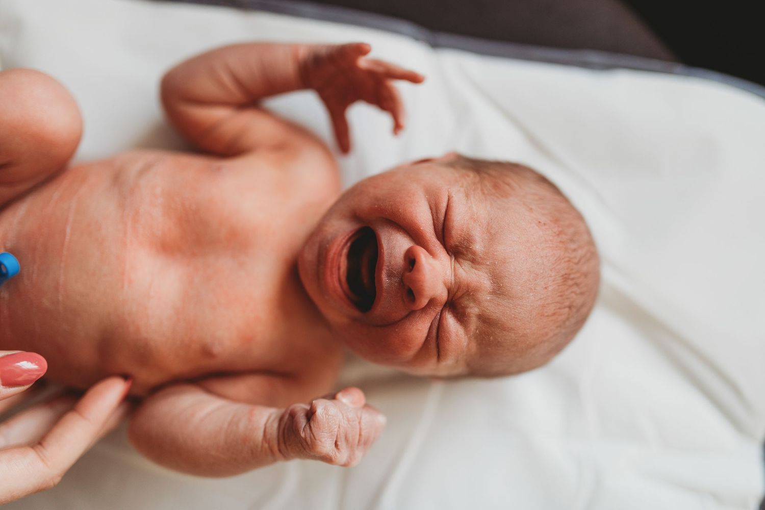 Multiple views of a sleeping newborn baby lying on white bedding in natural light.